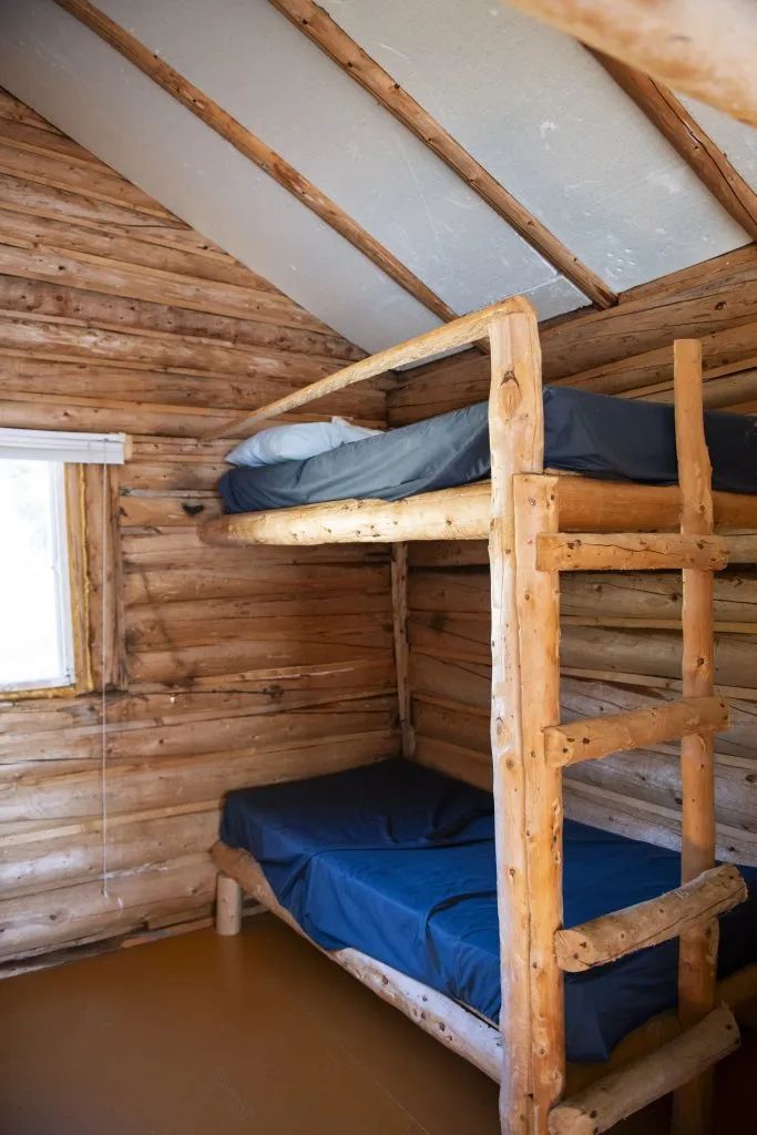 Une chambre avec des lits superposés en bois rond dans le chalet numéro trois.