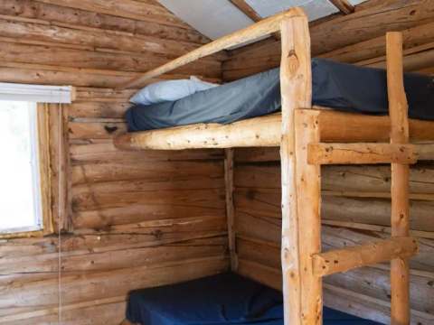 Une chambre avec des lits superposés en bois rond dans le chalet numéro trois.