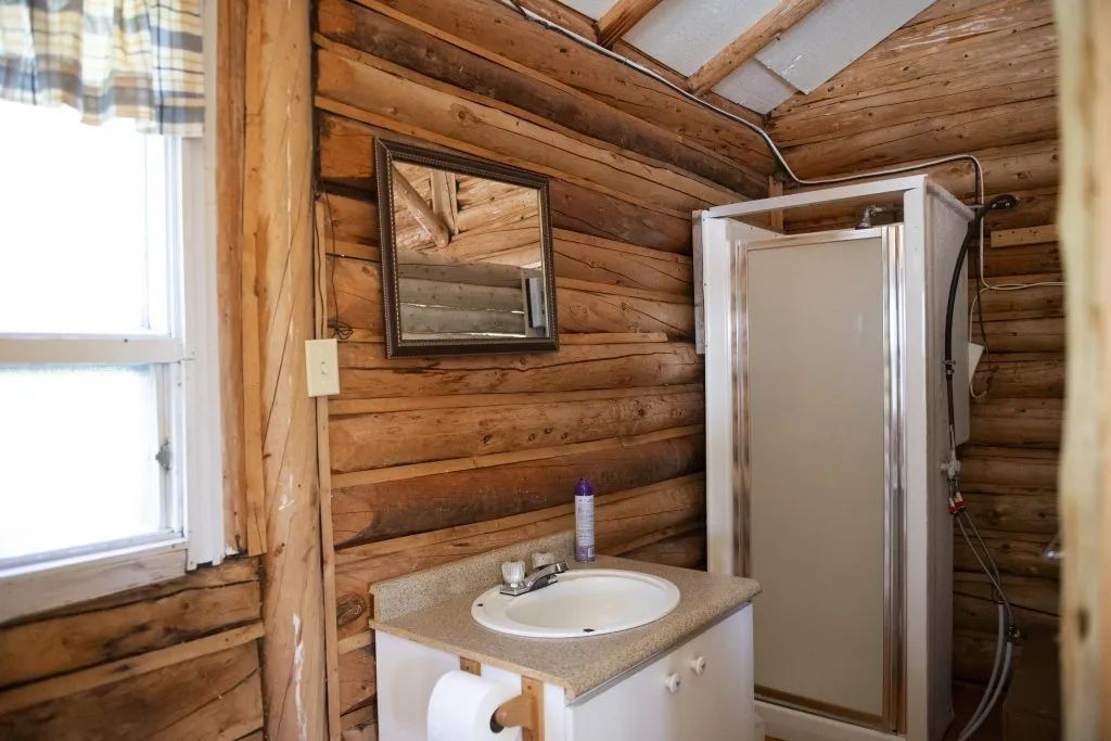 La salle de bain du chalet comprend une douche et un lavabo intégrés dans un décor en bois rond.
