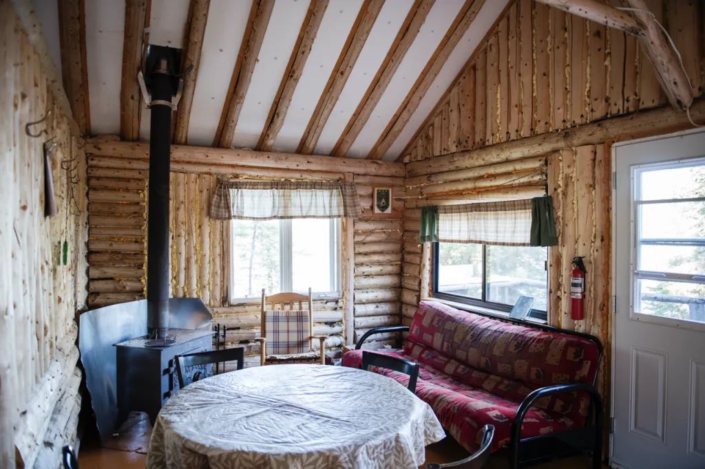 L'espace de vie du chalet comprend une table à manger et un poêle à bois pour votre confort.
