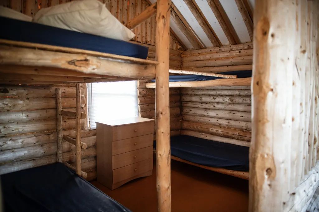 L'intérieur du chalet propose des lits superposés en bois rond rustique.