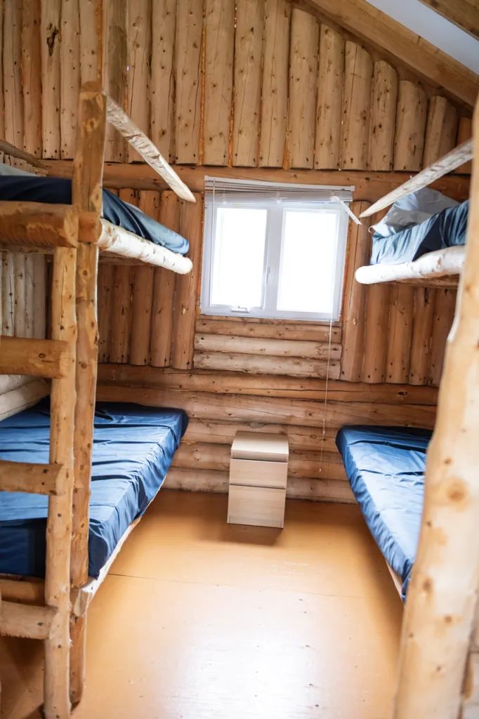 Cette chambre rustique en bois rond propose des lits superposés simples pour votre séjour.