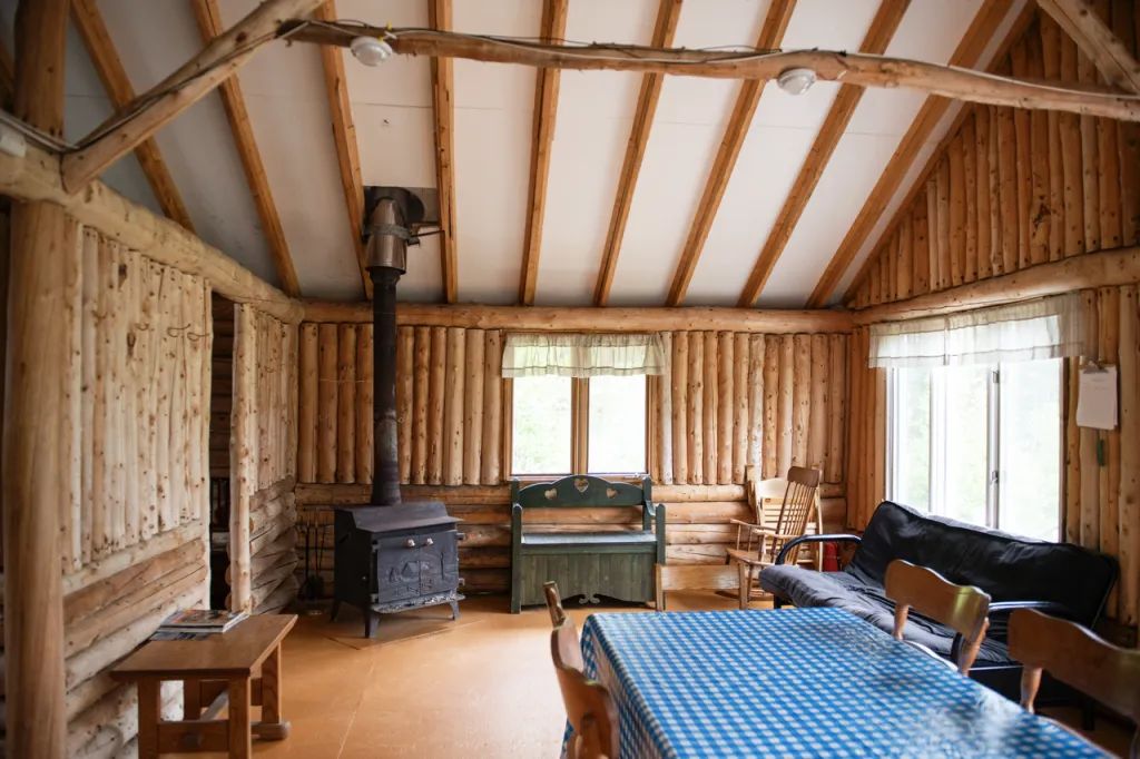 Le salon chaleureux du chalet comprend un poêle à bois et une table à manger.