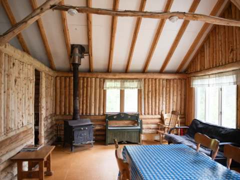 Le salon chaleureux du chalet comprend un poêle à bois et une table à manger.