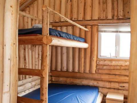 Cette chambre rustique du chalet 6 dispose de lits superposés en bois rond.