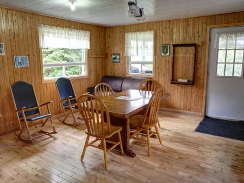 La salle à manger du chalet dispose d'une table en bois, de chaises et de fauteuils berçants.