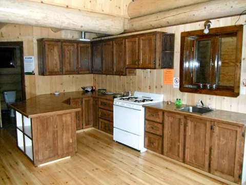 La cuisine équipée du chalet comprend des armoires en bois, un comptoir fonctionnel et une cuisinière.