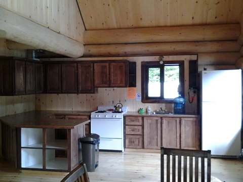 La cuisine équipée du chalet Le Pygargue offre un espace fonctionnel avec ses murs en bois rond.