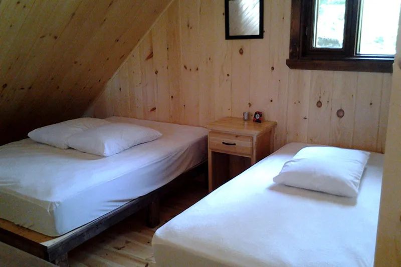 Vue sur la chambre mansardée équipée de deux lits dans le chalet Le Pygargue.