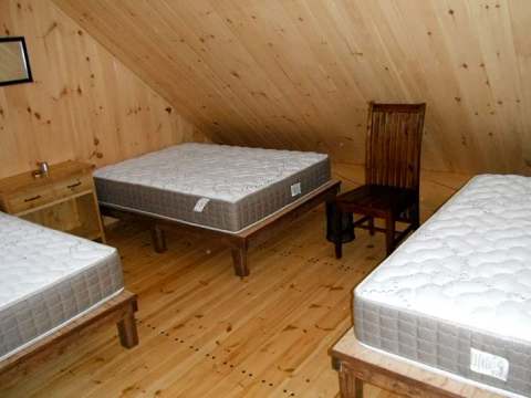La mezzanine du chalet Le Pygargue est aménagée avec trois lits simples.