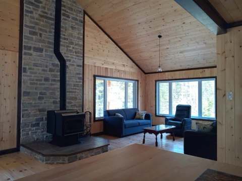The Le Touladi cottage living room features a wood stove and large bright windows.