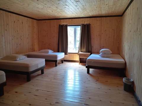 View inside a rustic bedroom with multiple wooden beds at Le Touladi cabin.