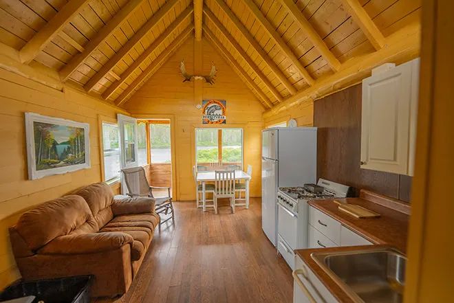 L'aire ouverte du chalet comprend une cuisine fonctionnelle, un salon avec divan et une salle à manger.