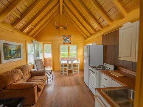 L'aire ouverte du chalet comprend une cuisine fonctionnelle, un salon avec divan et une salle à manger.