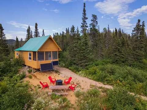 Vue aérienne du chalet numéro un entouré par la forêt avec un espace extérieur aménagé.