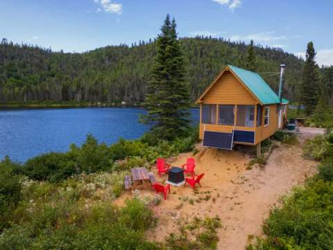 Le chalet numéro 1 est situé au bord de l'eau avec un coin foyer extérieur et une table de pique-nique.