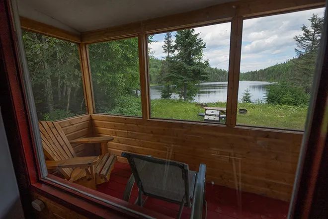 Vue sur le lac depuis la véranda grillagée du chalet.