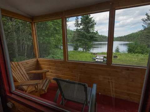 Vue sur le lac depuis la véranda grillagée du chalet.