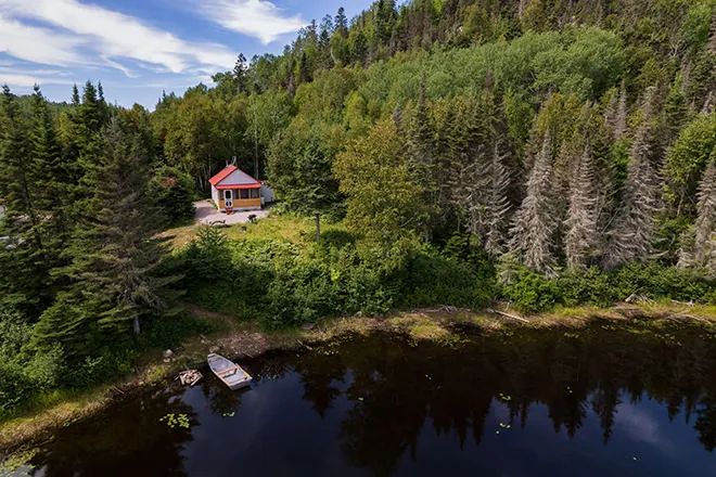 Aerial view of chalet number one located by the water, surrounded by the forest.
