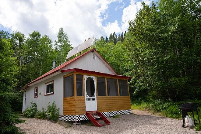 Le chalet numéro 3 dispose d'une galerie moustiquaire et est entouré par la forêt.
