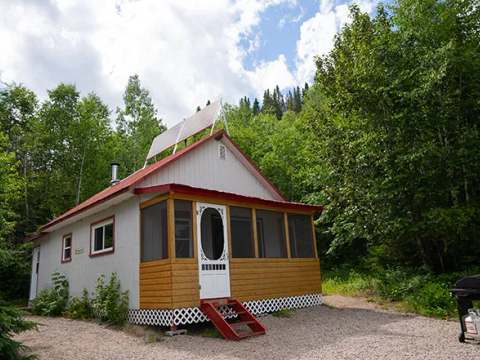 Le chalet numéro 3 dispose d'une galerie moustiquaire et est entouré par la forêt.
