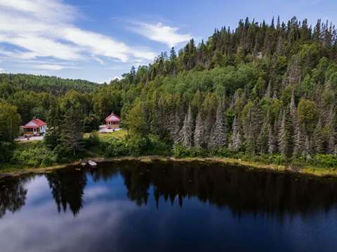 Vue aérienne des chalets situés en bordure du lac et entourés par la forêt.