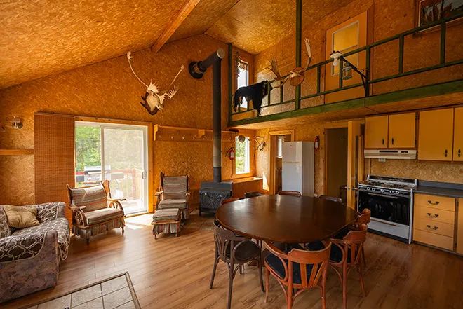 L'aire ouverte du chalet comprend une cuisine équipée, un coin repas et un salon avec foyer au bois.