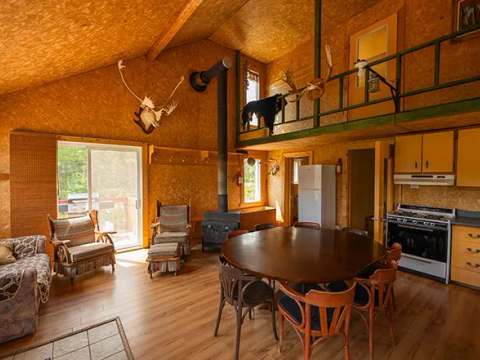 L'aire ouverte du chalet comprend une cuisine équipée, un coin repas et un salon avec foyer au bois.