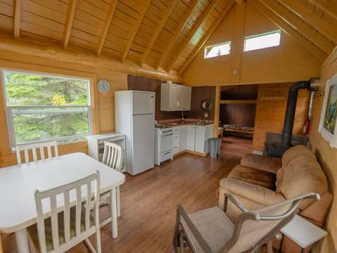 Vue d'ensemble de l'aire de vie principale du chalet, incluant la cuisine, la salle à manger et le salon.