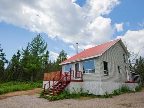 Vue extérieure du chalet numéro 4, incluant sa terrasse en bois et son toit rouge.
