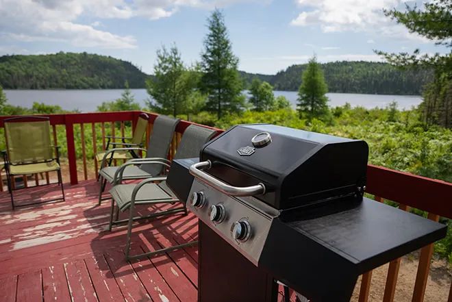 Le BBQ et les chaises sur la terrasse du chalet offrent une vue panoramique sur le lac.
