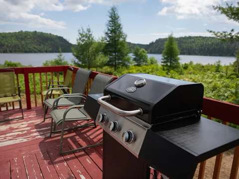 Le BBQ et les chaises sur la terrasse du chalet offrent une vue panoramique sur le lac.