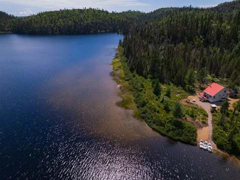 Vue aérienne du chalet numéro cinq situé au bord d'un lac entouré de forêt.