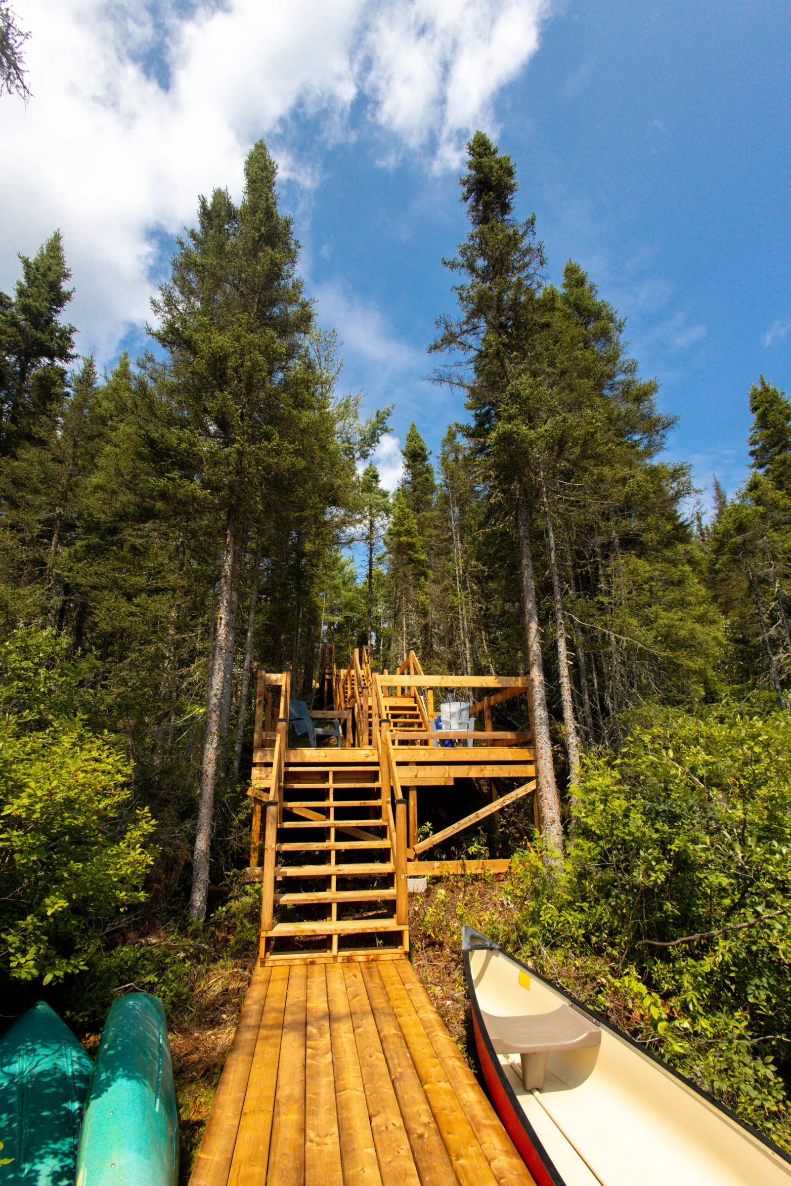 Des escaliers en bois mènent du quai jusqu'à la terrasse aménagée du chalet.