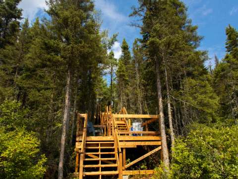 Des escaliers en bois mènent du quai jusqu'à la terrasse aménagée du chalet.