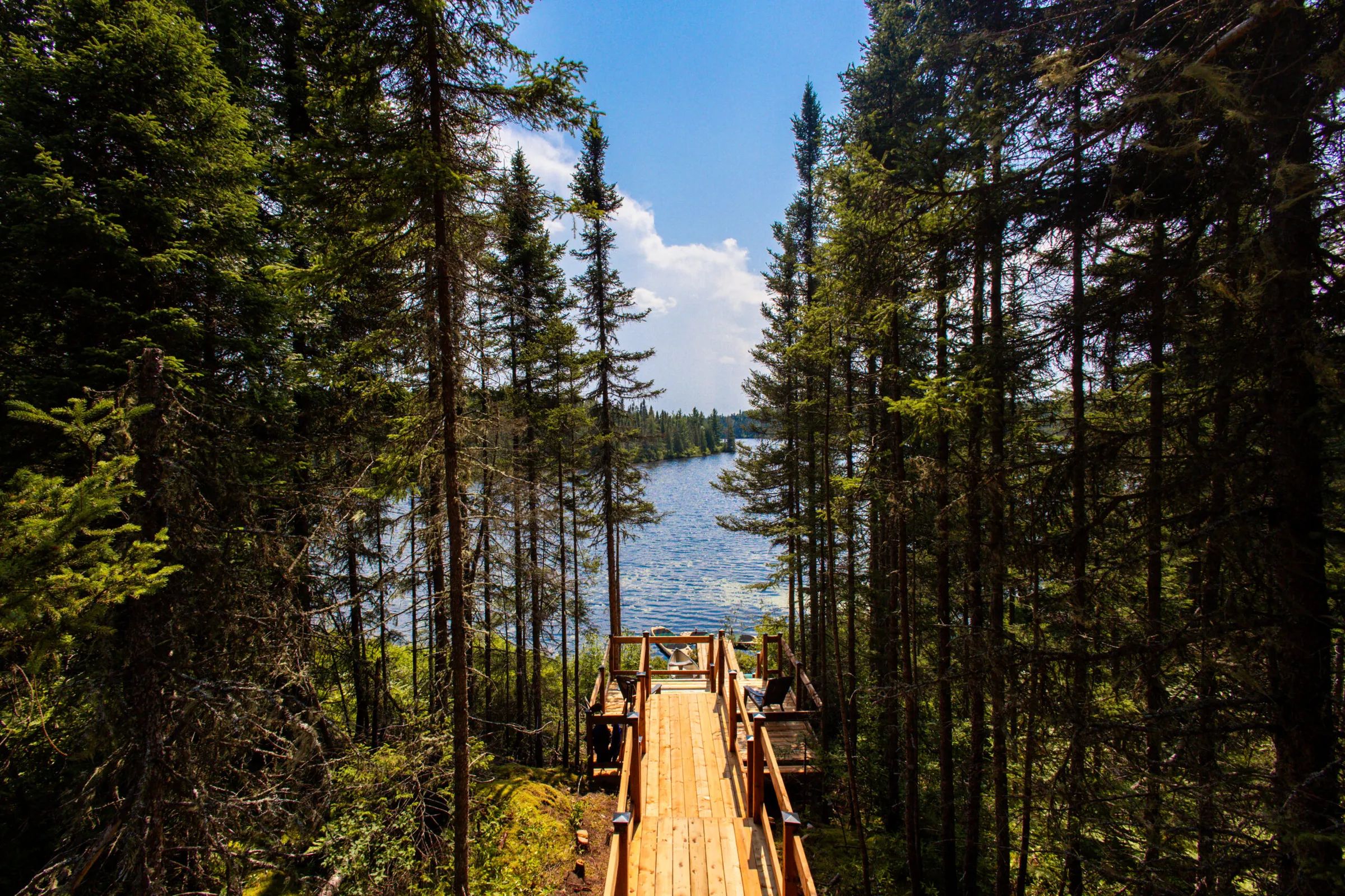 Un sentier de bois mène directement au quai privé du chalet en bordure de lac.