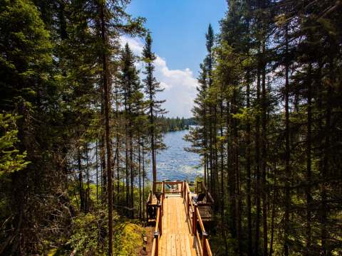 Un sentier de bois mène directement au quai privé du chalet en bordure de lac.