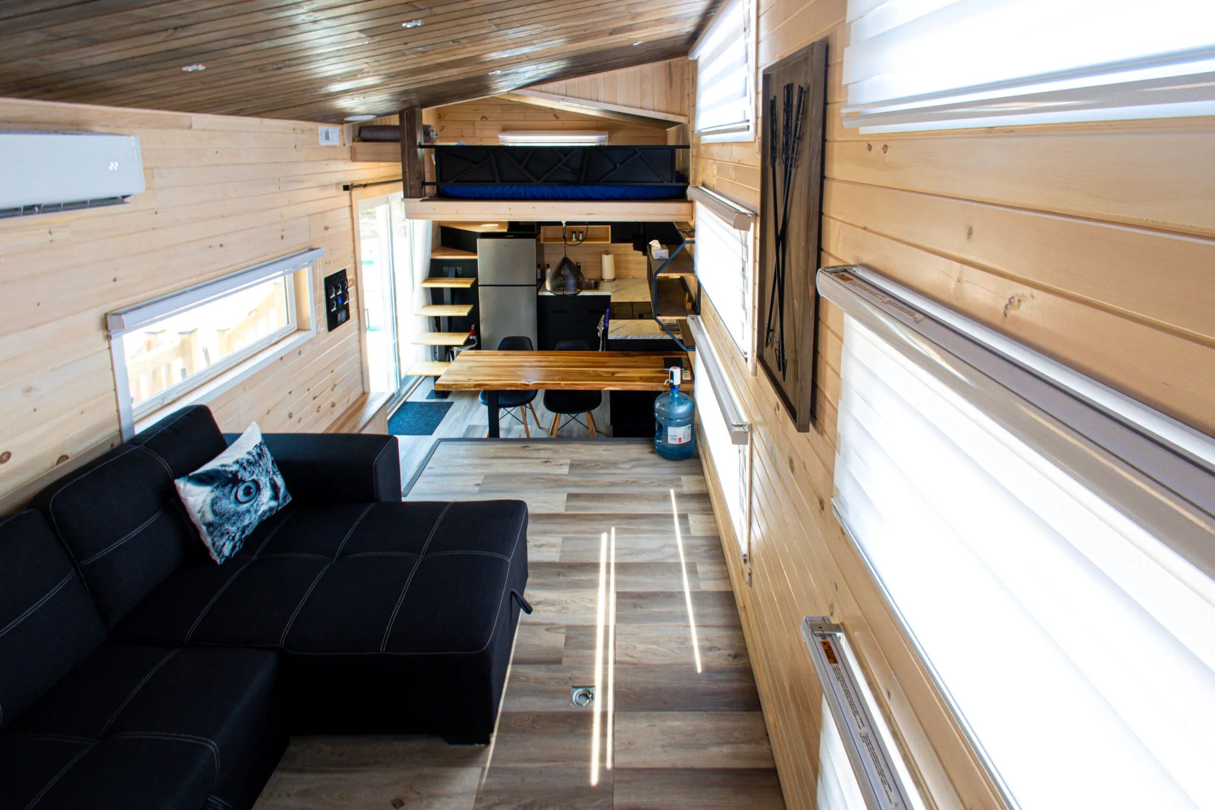 Overview of the tiny house interior with a living area, kitchen, and mezzanine.