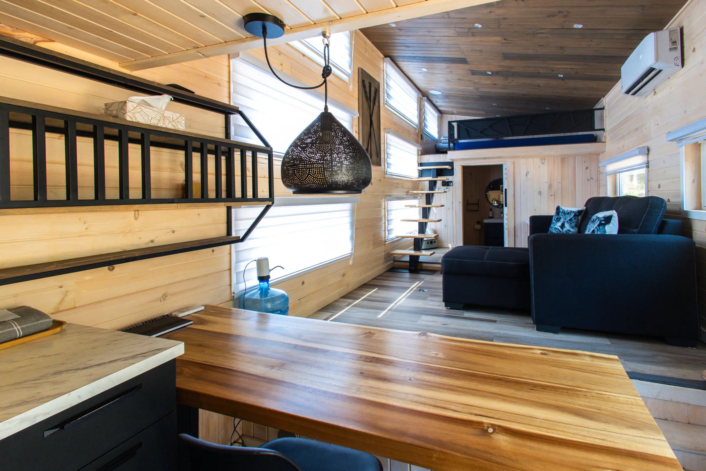 View of the bright living area with table, lounge, and mezzanine in the tiny house.