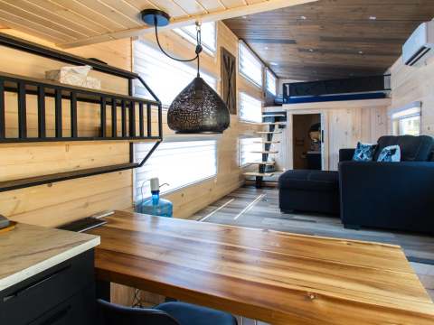 View of the bright living area with table, lounge, and mezzanine in the tiny house.