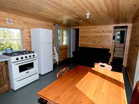 L'aire ouverte du chalet comprend une cuisine équipée, une table à manger et un salon.