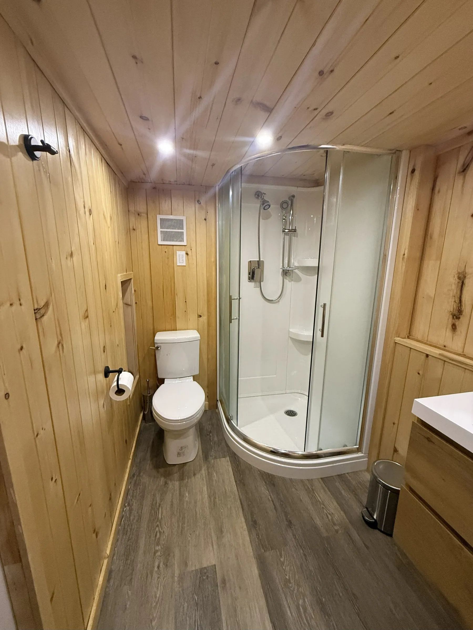This private bathroom includes a modern shower and a toilet in a wooden decor.