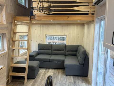 The living room of cottage 8 features a comfortable sofa and a mezzanine accessible by a wooden ladder.