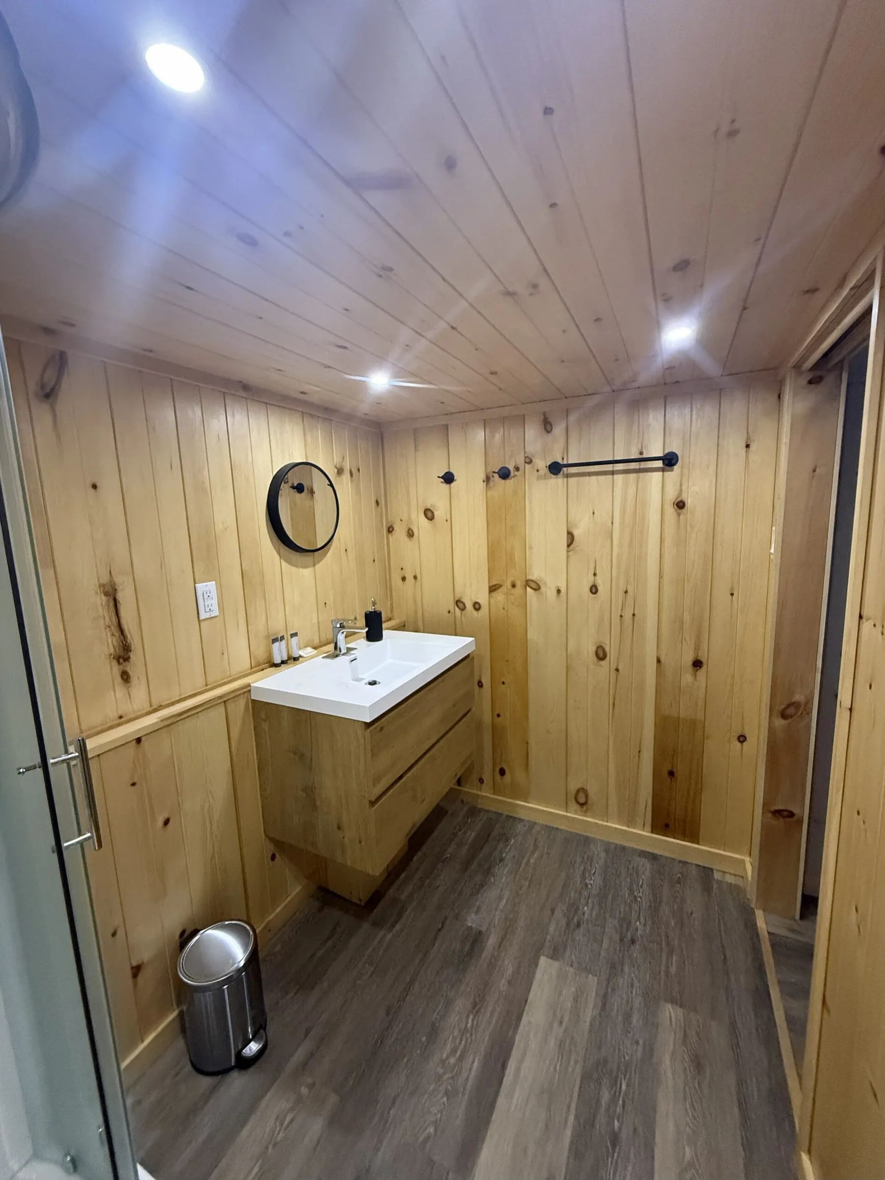 The cottage bathroom features a modern vanity and wood-paneled walls.