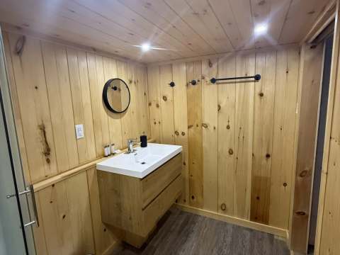 The cottage bathroom features a modern vanity and wood-paneled walls.