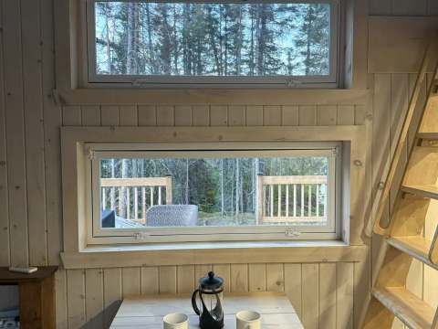A wooden table with cups and a coffee maker in front of a window at cottage 8.