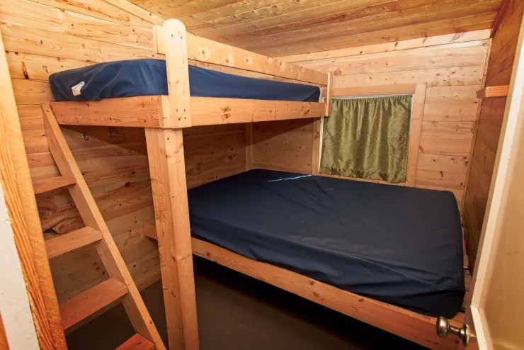 Cette chambre de chalet comprend un lit superposé avec des matelas simples.