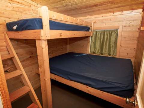 Cette chambre de chalet comprend un lit superposé avec des matelas simples.