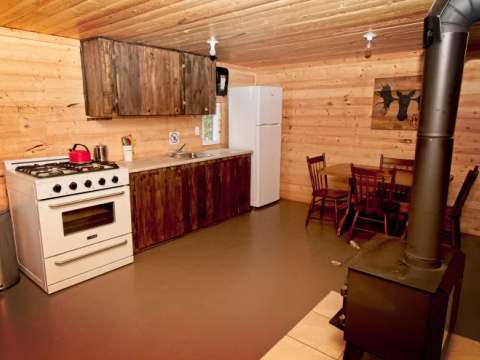La cuisine équipée et l'espace repas du chalet 1 en bois rond.