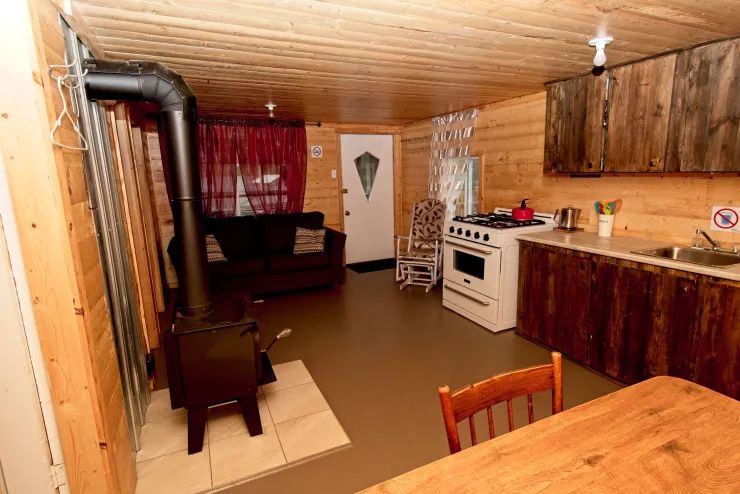 Vue d'ensemble de l'aire de vie principale comprenant la cuisine, le salon et le poêle à bois.